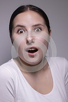 Suprised brunette woman, isolated on gray background. happy actress portrait. human emotions, facial expression concept