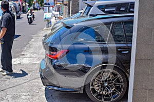 Black BMW M3 Competition Touring xDrive G81 on car workshop