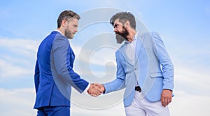 Sure sign you should trust business partner. Men formal suits shaking hands blue sky background. Business deal approved