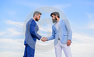 Sure sign you should trust business partner. Men formal suits shaking hands blue sky background. Entrepreneurs shaking