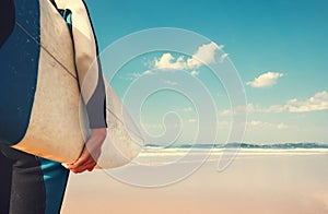 Surf board in surfer`s hand close up image with oceans waves vie