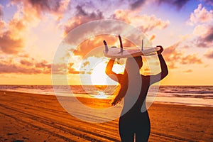 Surf girl with long hair go to surfing. Woman with surfboard on a beach at sunset.