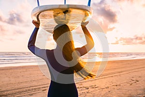 Surf girl with long hair go to surfing. Woman with surfboard on a beach at sunset or sunrise. Surfer and ocean