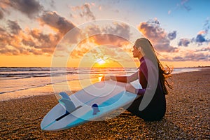 Surf girl and ocean. Beautiful young woman surfer girl with surfboard on a beach at sunset or sunrise.