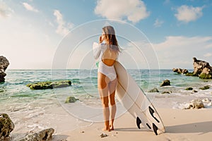 Surf girl with surfboard looking at ocean. Beautiful surfer woman at beach.