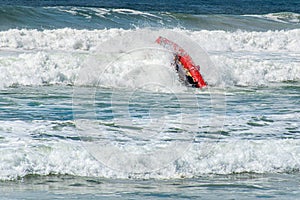 Surf rescue life savers boat upside down in the waves