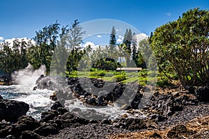 Surf and volcanic rock formations below cottage in a tropical setting