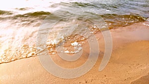 Surf of waves ashore on the yellow sand of the beach.