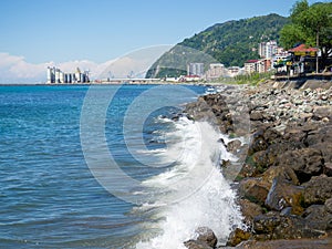 Surf. Waves crash on big rocks. Rocky coast and wave. Fortified coastline. View of the city