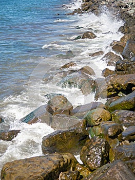 Surf. Waves crash on big rocks. Rocky shore and splashing waves. Powerful coastline. Sea foam. The excitement of the sea