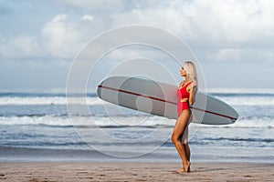 Surf woman with long blonde hair go to ocean.