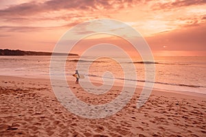 Surf woman with surfboard go to ocean for surfing. Surfer woman on beach at bright sunset