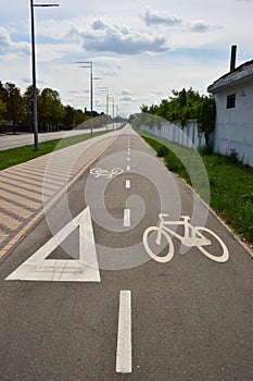On the surface of the asphalt road, a sign for cyclists in both directions to allow traffic to pass