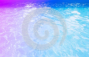 Surface of blue swimming pool toned in multicolored neon. Background of water in swimming pool