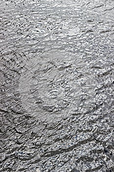 Surface of blue water with small ripples. Not a calm river surface. Vertical background