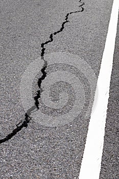 Surface cracks paved rural road near the white line