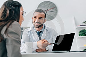 surface level of doctor pointing on laptop with blank screen to patient