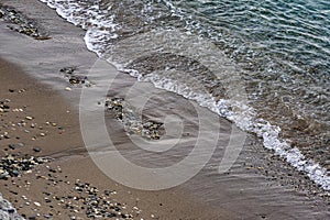 The surface is salty sea water, swaying in small waves near the shore, through the transparent bottom you can see stones