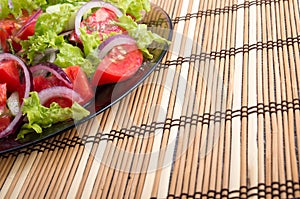 Surface of the table and a plate of fresh vegetarian salad