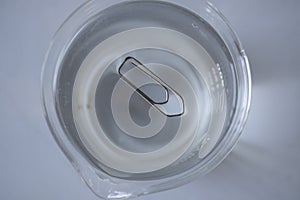 Surface tension of water. Paper clip floats on water in the laboratory