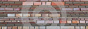 Varicolored flat stones of regular shape in the wall construction. Panorama