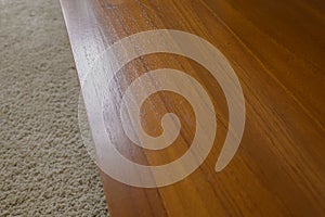 Surface view of teak table against beige carpet.