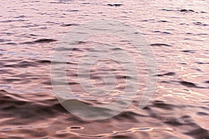 Surface of water with waves background texture, wave close up, light playing on the sea surface, the surface of golden water at