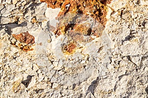 Surface of a white crumbled rock with red spot illuminated by a bright sun. Abstract stone background for texture