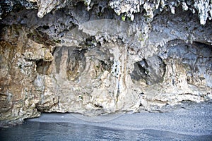 Surfaced cliff with stalactites, stalagmites, paleolithic fossils, and a small shingle beach. photo