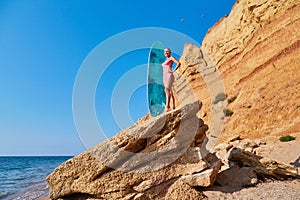 Surfboard for active sport. Lady sunbathing on stone. Idea of surfing, summer, vacation trip and relax time, copy space