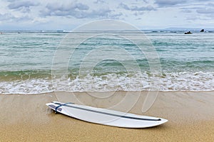 Surfboard lying on sand near the ocean photo
