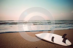 Surfboard on tropical beach at sunset in summer.