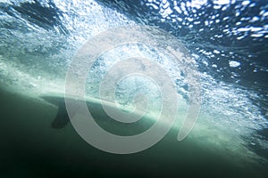 Surfboard underwater with fin and air bubbles