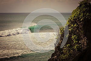 Surfer on a barrel wave getting tubed on his surfboard