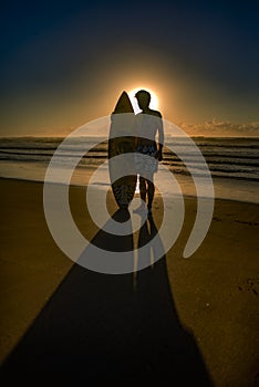 Surfer on Beach with Sun Directly from Behind