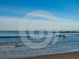 Surfer embarks into ocean to ride small waves on beach