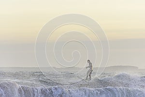 Surfer enjoying evening surf in rough sea at sunset getting splashed by water