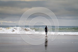 A surfer entering the sea at the Carcavelos Beach in Oeiras