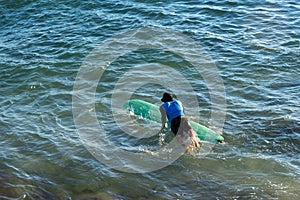 Surfer entering the sea from Farol da Barra beach. Salvador, Bahia, Brazil