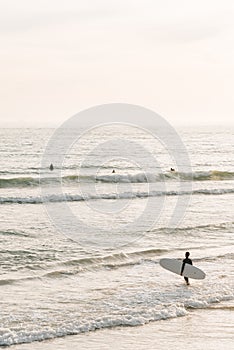 A surfer enters the Pacific Ocean, in Newport Beach, Orange County, California