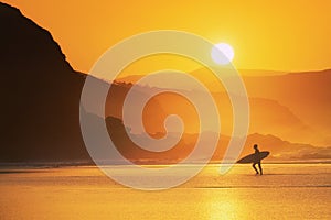 Surfer exiting water at sunset photo
