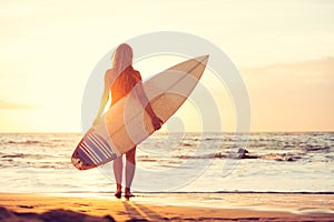 Surfer girl on the beach at sunset