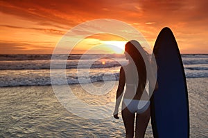 Surfer girl on beach at sunset