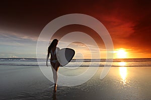 Surfer girl on beach at sunset