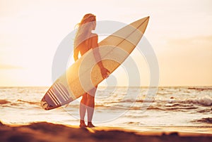 Surfer girl on the beach at sunset