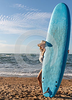 Surfer girl on the beach at sunset with a blue longboard