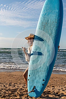 Surfer girl on the beach at sunset with a blue longboard