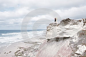 Surfer girl on cliff near ocean
