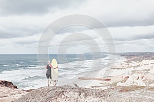 Surfer girl on cliff near ocean