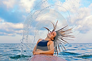 Surfer girl flip long wet hair with splashes in air